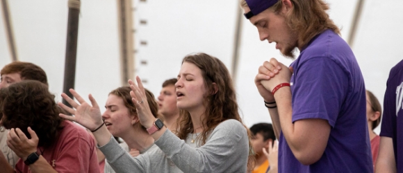 Students in a crowd praying
