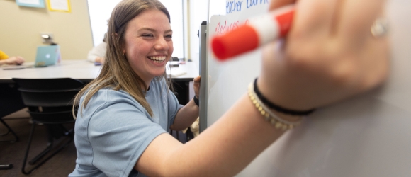 Smiling woman writing on a dry-erase board
